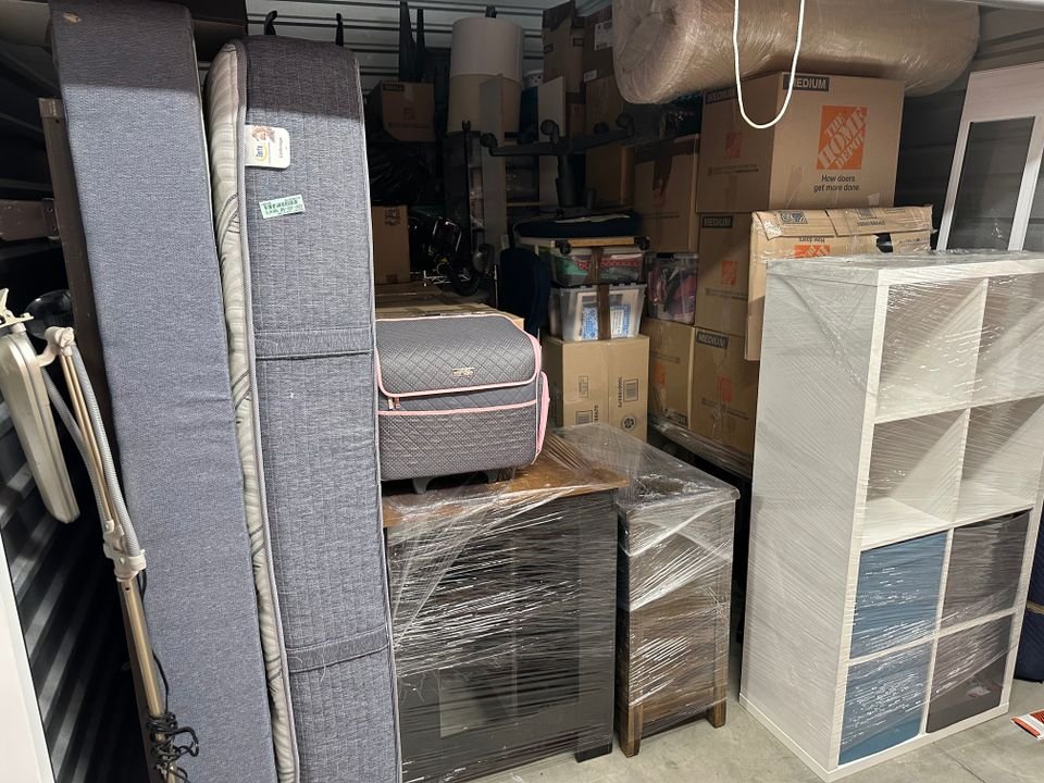 Professional movers carrying wrapped furniture out of a house